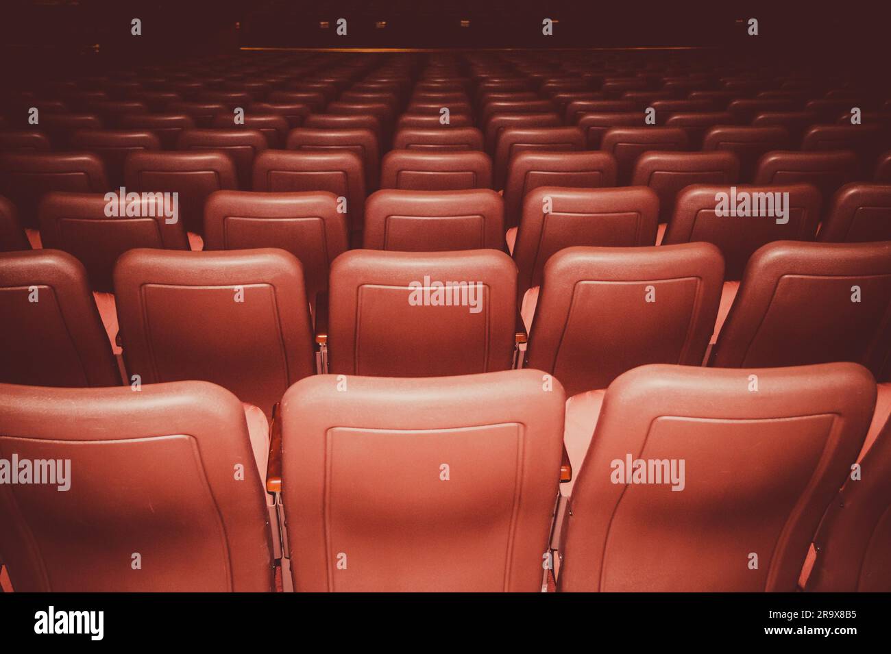Sièges de cinéma en couleurs rouge dans une pièce sombre Banque D'Images