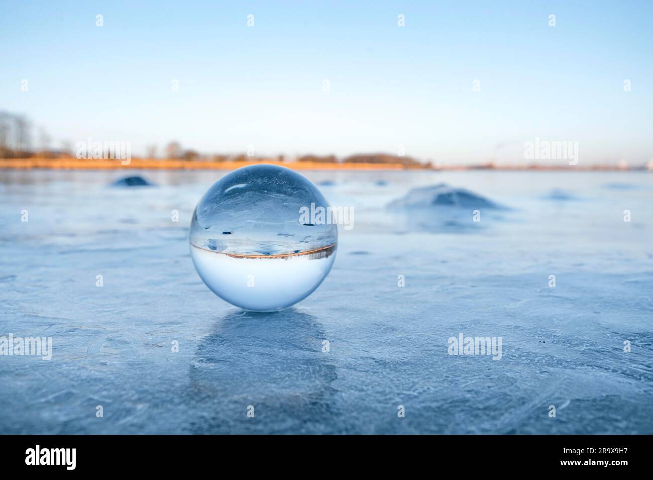Orbe de verre transparent sur un lac gelé avec la glace en hiver Banque D'Images