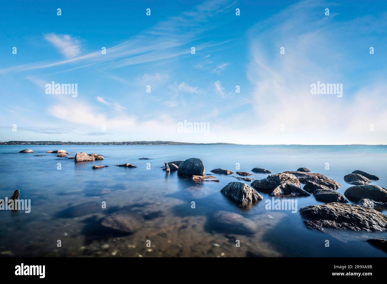 Rochers au bord de l'océan dans l'eau calme sous un beau ciel bleu Banque D'Images
