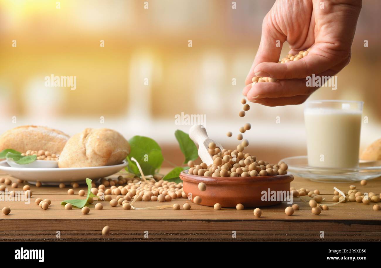 Déposez les graines de soja sur une table en bois avec des produits de soja et la cuisine en arrière-plan. Vue avant. Banque D'Images
