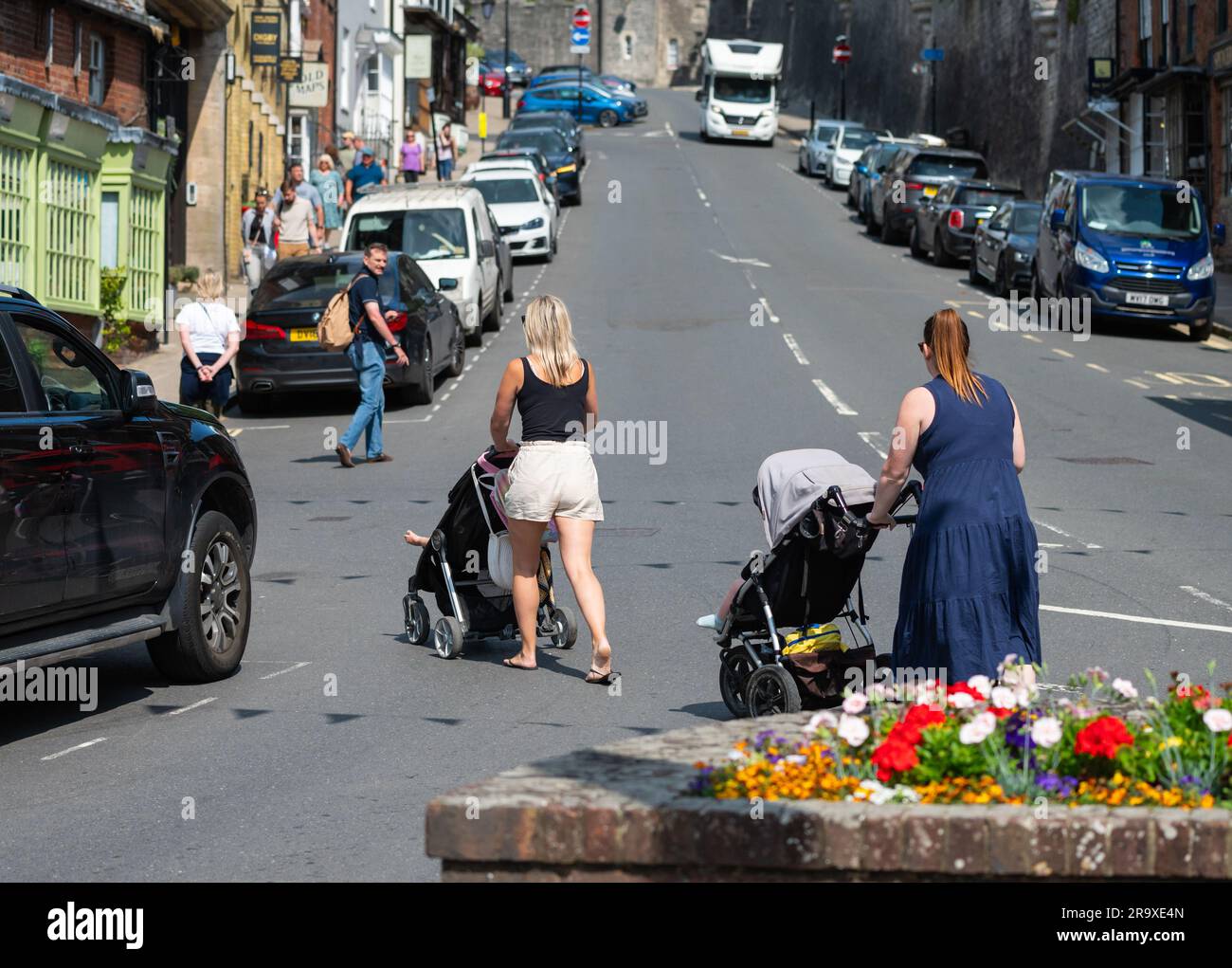 Des femmes avec des enfants dans des poussettes, probablement des mères, les poussant sur une route britannique sans voitures venant en Angleterre, au Royaume-Uni. Banque D'Images
