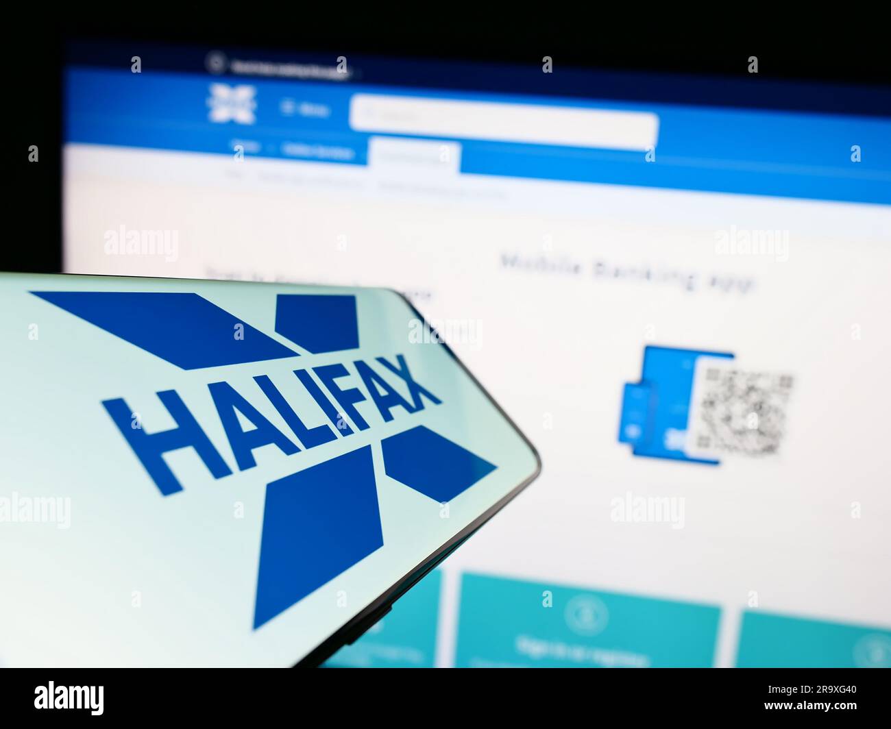 Téléphone mobile avec logo de la société britannique de services financiers Halifax à l'écran devant le site Web. Effectuez la mise au point au centre-droit de l'écran du téléphone. Banque D'Images