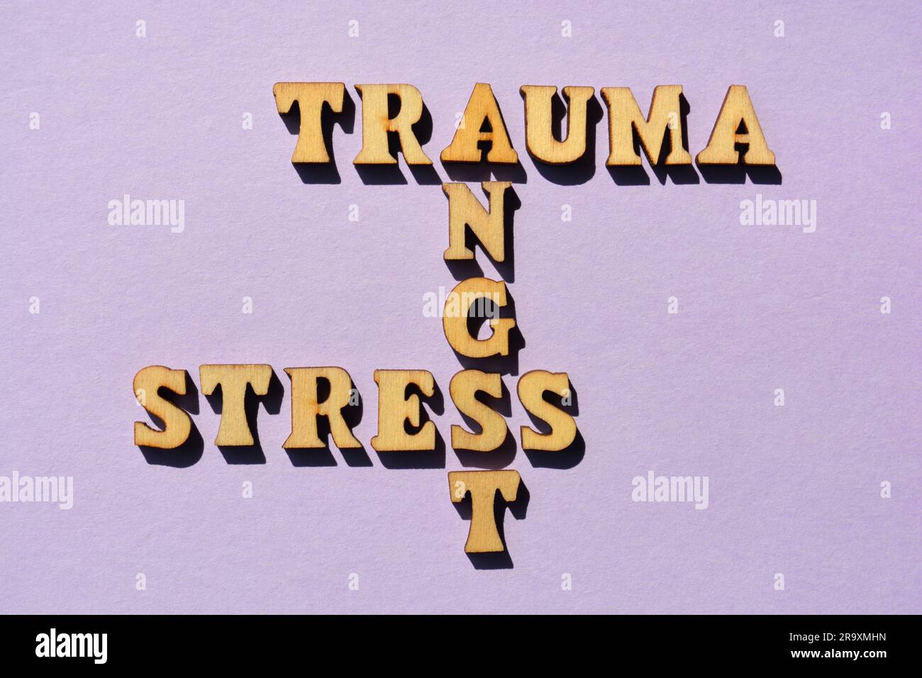 Trauma, stress, Angst, mots en lettres de l'alphabet en bois sous forme de mots croisés isolés sur fond lilas Banque D'Images