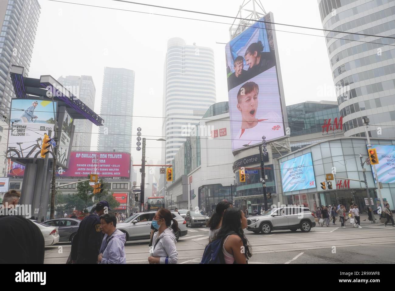 Toronto, Ontario/Canada - 28 juin 2023 : avec un indice de qualité de l'air très faible de PM 2,5 (plus de 200) et 10, en raison des feux de forêt dans le nord et l'ouest, les Torontois et les voitures bravent les risques sains et traversent l'intersection très fréquentée du centre-ville de Yonge et Dundas. Certaines personnes portent des masques. Toronto a été considérée comme une ville parmi les plus polluées de l'air ce jour-là. Pour les utilisations éditoriales Banque D'Images