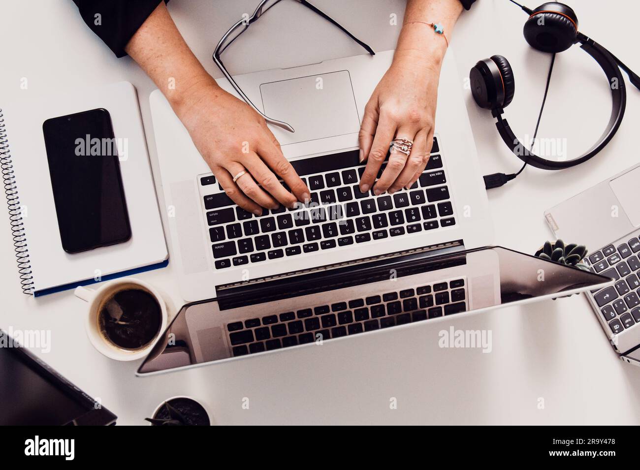 Une personne assise à un bureau avec son ordinateur portable et d'autres fournitures Banque D'Images