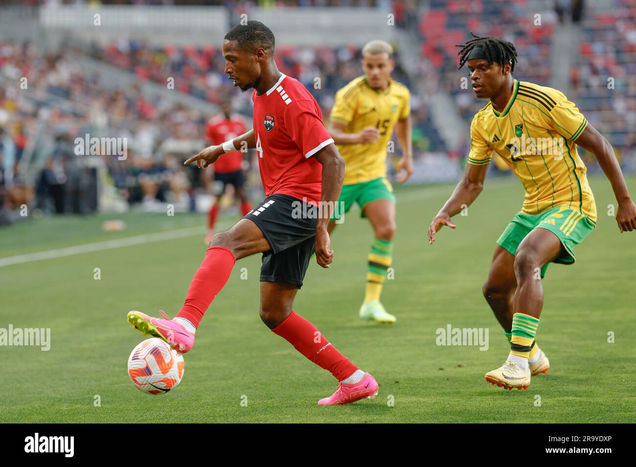 St. Louis, Missouri. USA; le défenseur de Trinité-et-Tobago, Shannon Gomez (14), dribbles le ballon sous la pression du défenseur jamaïcain Dexter Lembikisa (2) pendant Banque D'Images