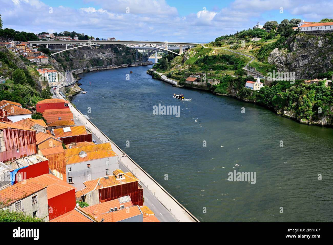 Vue sur Porto, Portugal, avec ses toits carrelés et le fleuve Douro avec ses ponts et son bateau touristique Banque D'Images