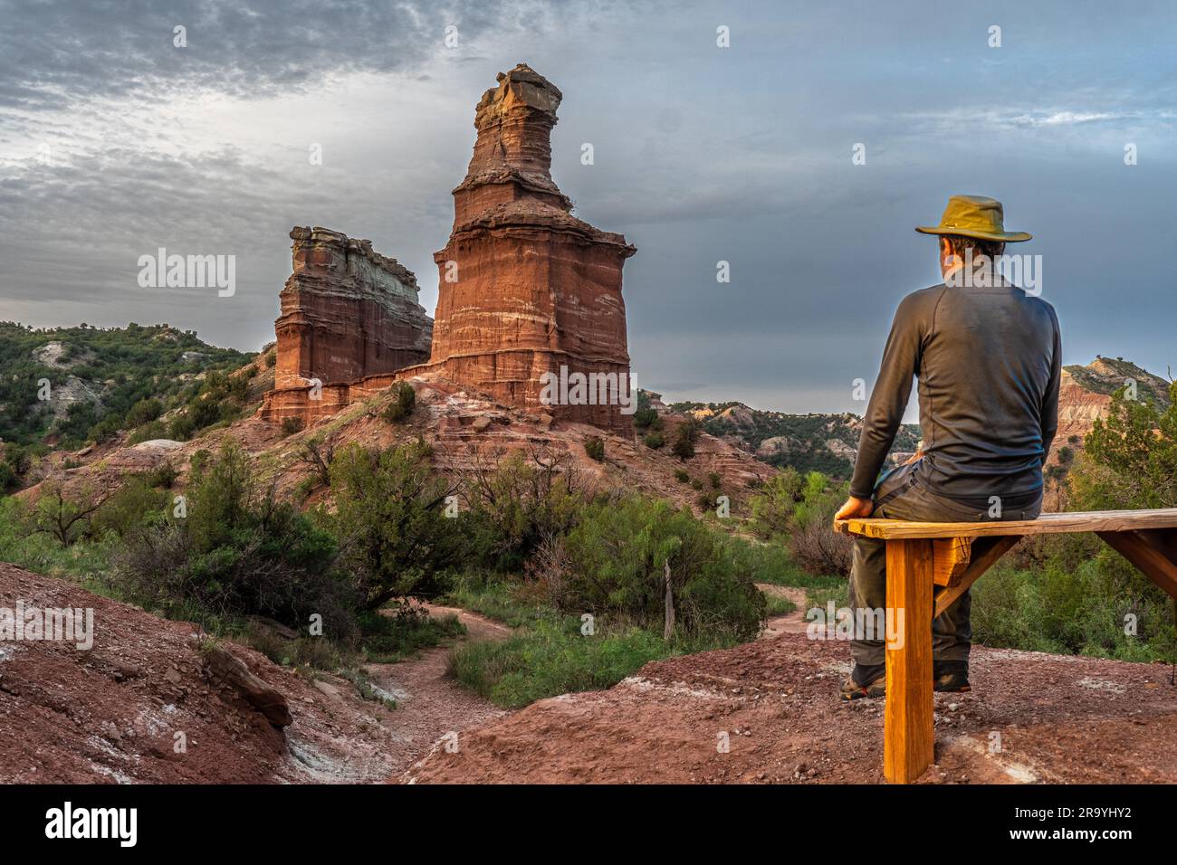 Homme mature randonneur caucasien assis sur un banc en bois regardant une magnifique grande tours de roche naturelle, le phare, parc national de Palo Duro Canyon, TX Banque D'Images