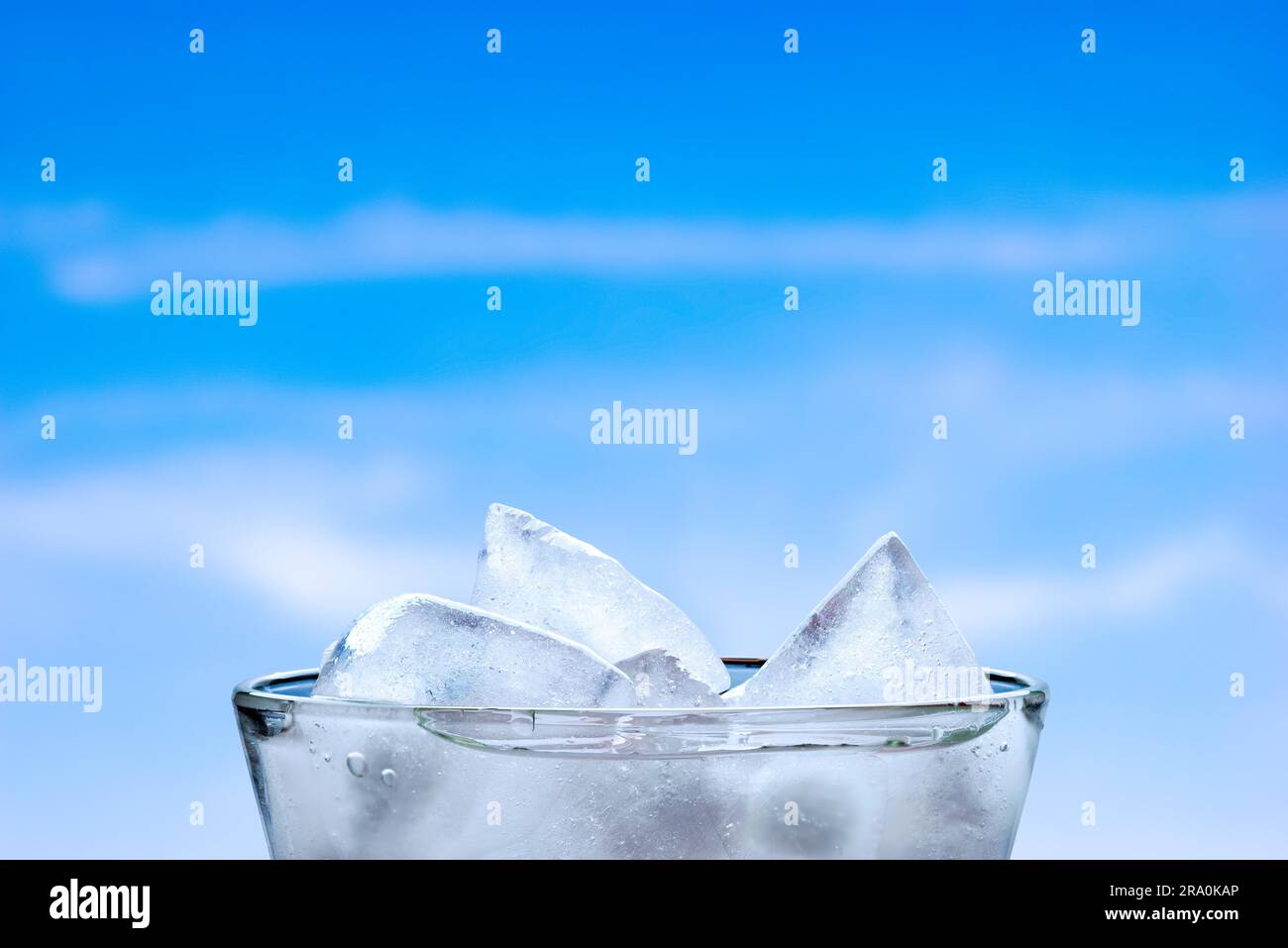 Des cubes de glace dans un verre d'eau fraîche, avec un ciel nuageux ciel d'été Banque D'Images