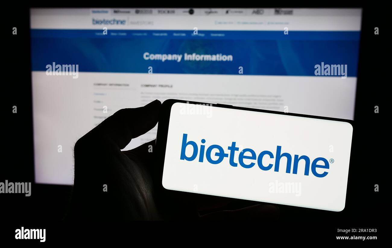 Personne tenant un smartphone avec le logo de la société américaine de sciences de la vie Bio-Techne Corporation à l'écran devant le site Web. Mise au point sur l'affichage du téléphone. Banque D'Images