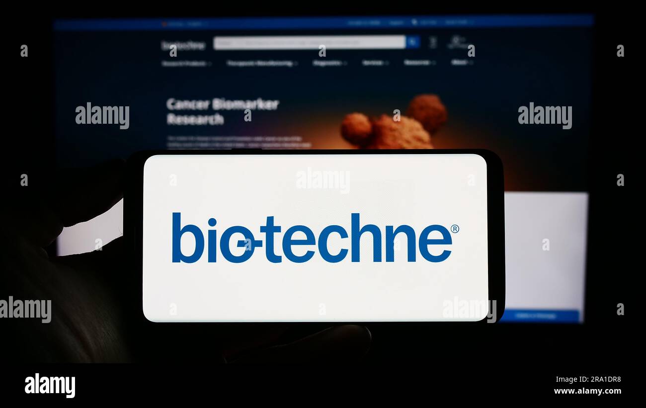 Personne tenant un téléphone portable avec le logo de la société américaine de sciences de la vie Bio-Techne Corporation à l'écran devant la page Web. Mise au point sur l'affichage du téléphone. Banque D'Images