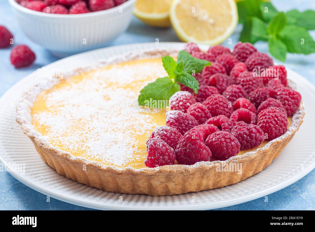 Tarte au citron maison, garnie de framboise fraîche, sucre glace et menthe, horizontale Banque D'Images