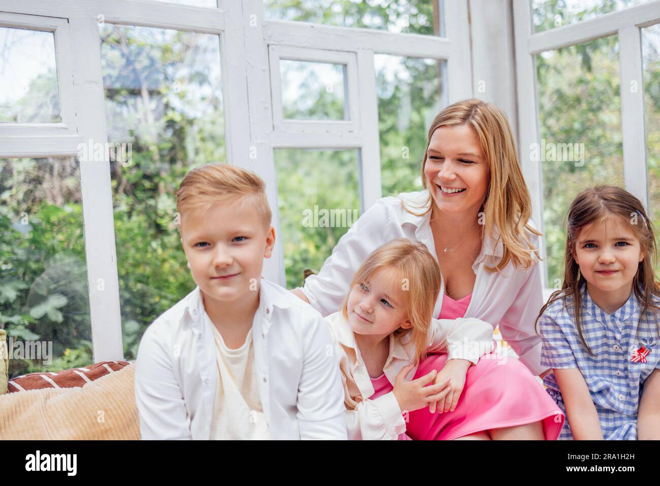 Une grande famille heureuse. Une jeune belle mère et ses trois enfants dans la maison d'été. Une belle femme blonde et ses enfants adorables apprécient la nature A. Banque D'Images