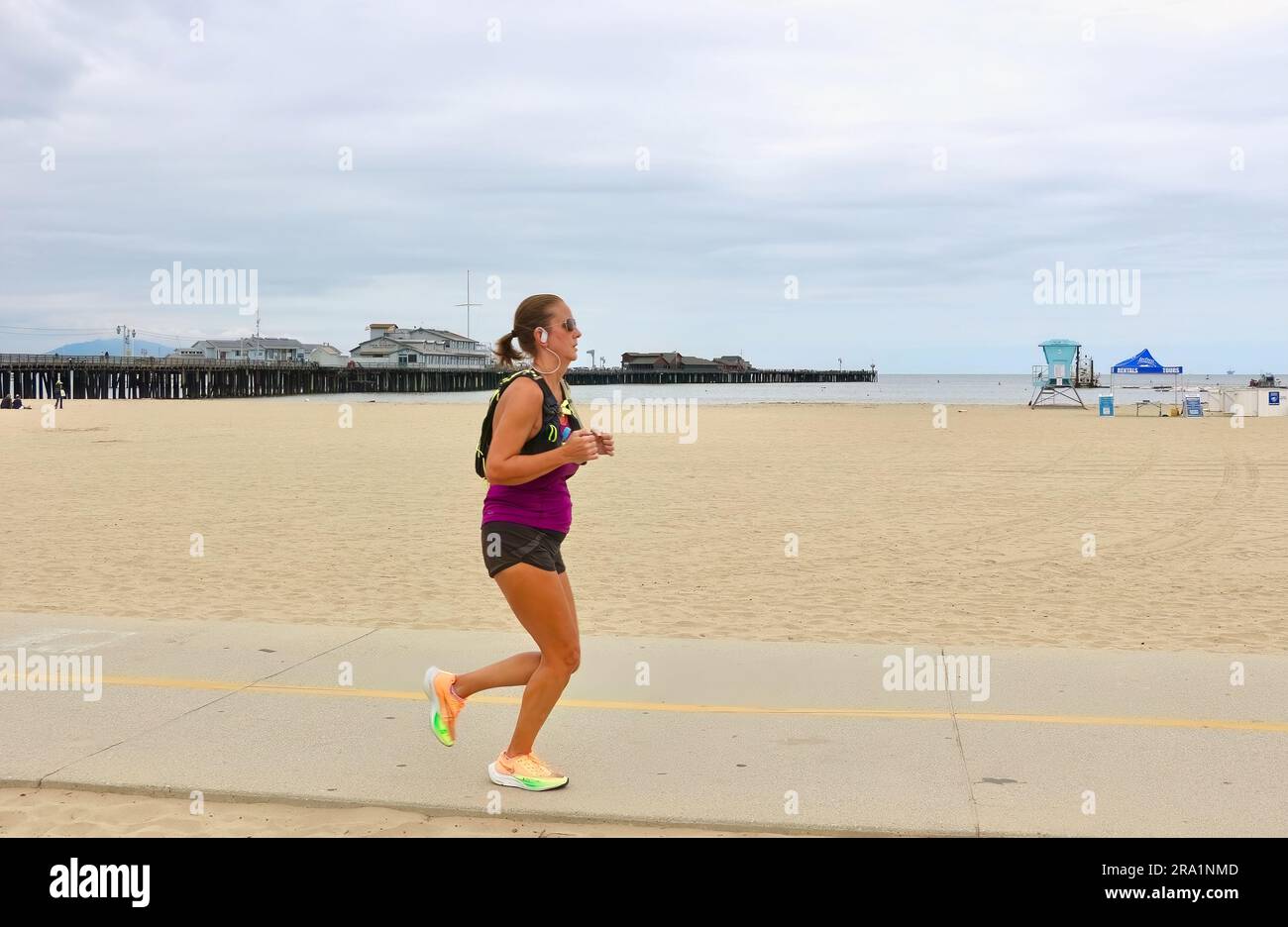 Jogger courant à côté d'une plage vide sur un froid après-midi de mai West Beach Santa Barbara Californie USA Banque D'Images
