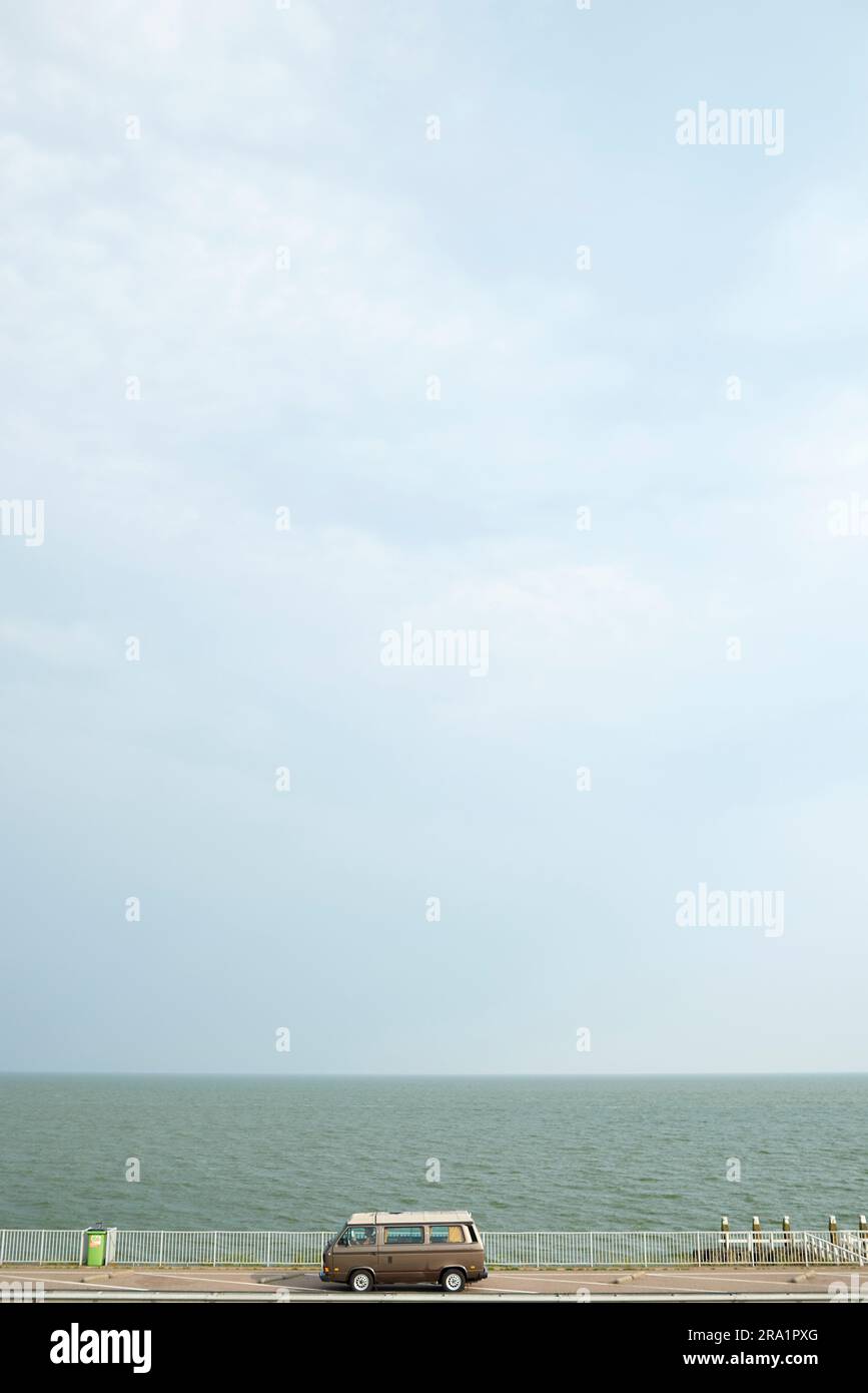 Fourgonnette Volkswagen d'époque garée à côté de l'océan sous le soleil d'été Banque D'Images