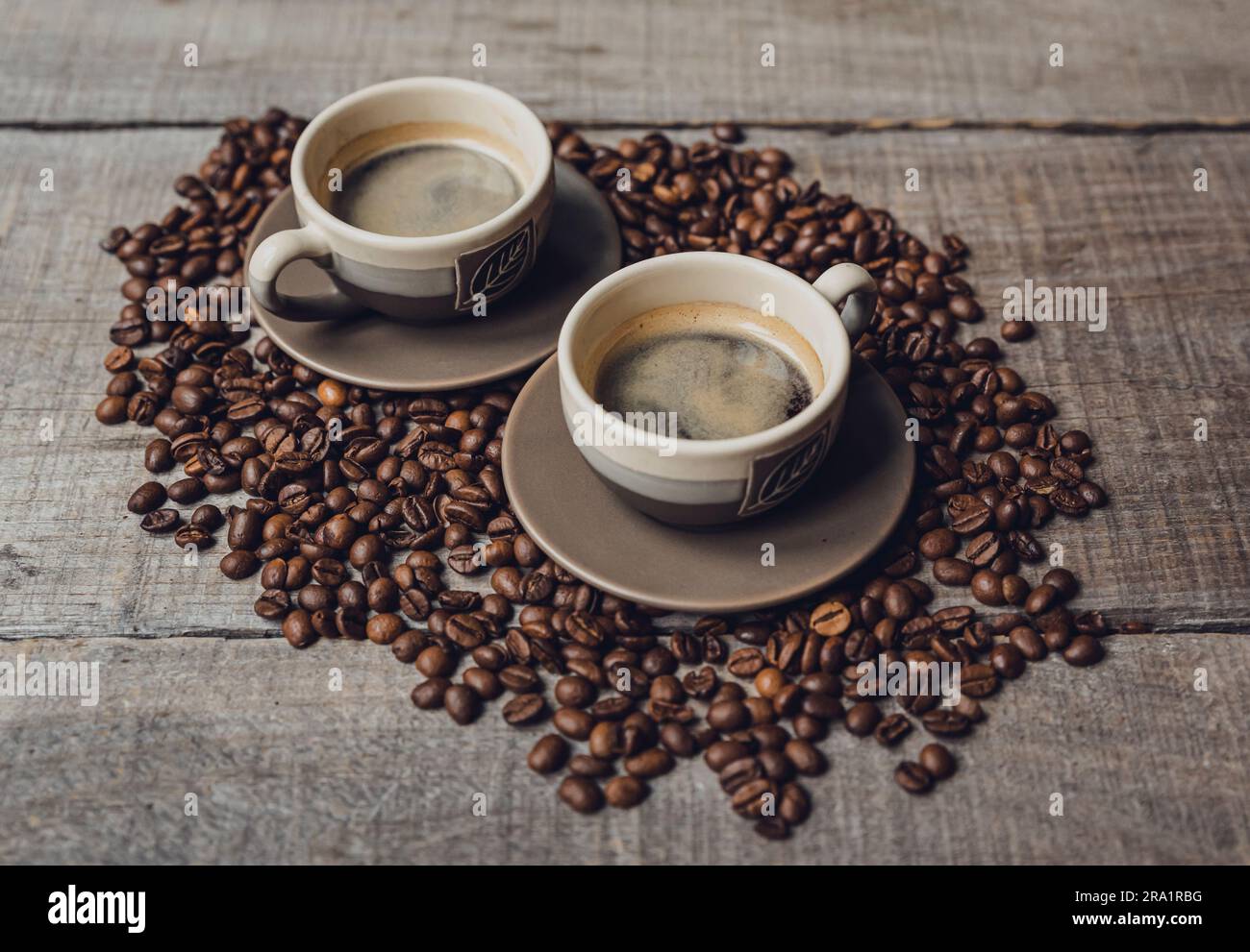 Deux tasses d'espresso placées sur une pile de grains de café sur une table en bois. Banque D'Images Deux tasses d'espresso placées sur une pile de grains de café sur une table en bois. Banque D'Images