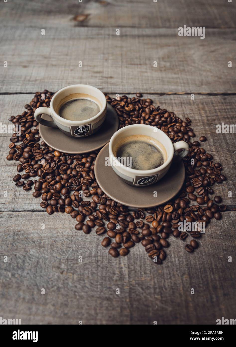 Deux tasses d'espresso sont placées sur une table en bois, au-dessus des grains de café. Banque D'Images Deux tasses d'espresso sont placées sur une table en bois, au-dessus des grains de café. Banque D'Images