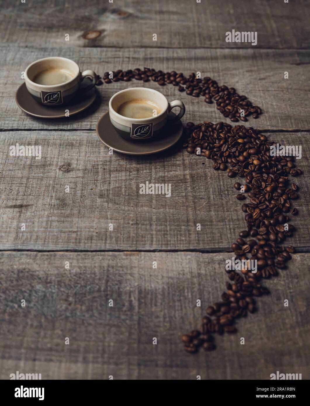 Grains de café menant à des tasses d'espresso sur une table en bois. Banque D'Images Grains de café menant à des tasses d'espresso sur une table en bois. Banque D'Images