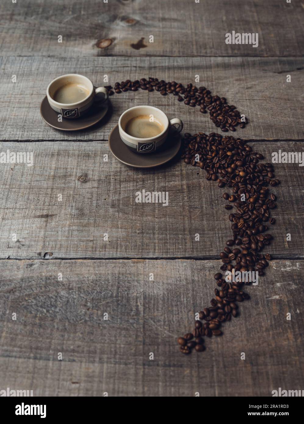 Grains de café conduisant à deux tasses d'espresso sur une table en bois. Banque D'Images Grains de café conduisant à deux tasses d'espresso sur une table en bois. Banque D'Images