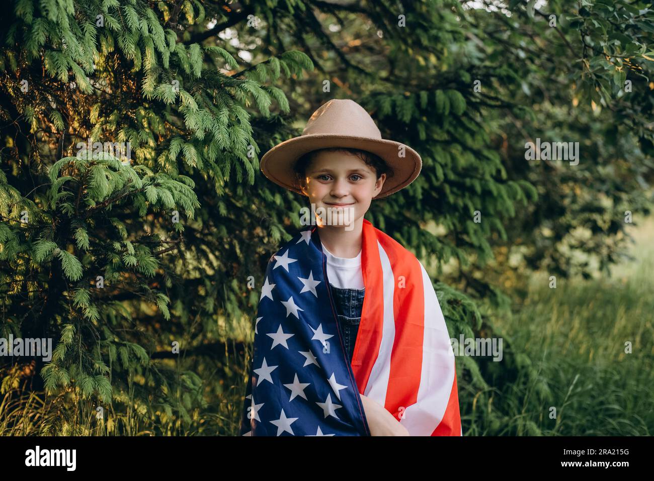 Portrait d'une petite fille souriante en chapeau célébrant le 4 juillet le jour de l'indépendance des États-Unis à la journée ensoleillée. Joli enfant avec drapeau américain des Etats-Unis. Banque D'Images