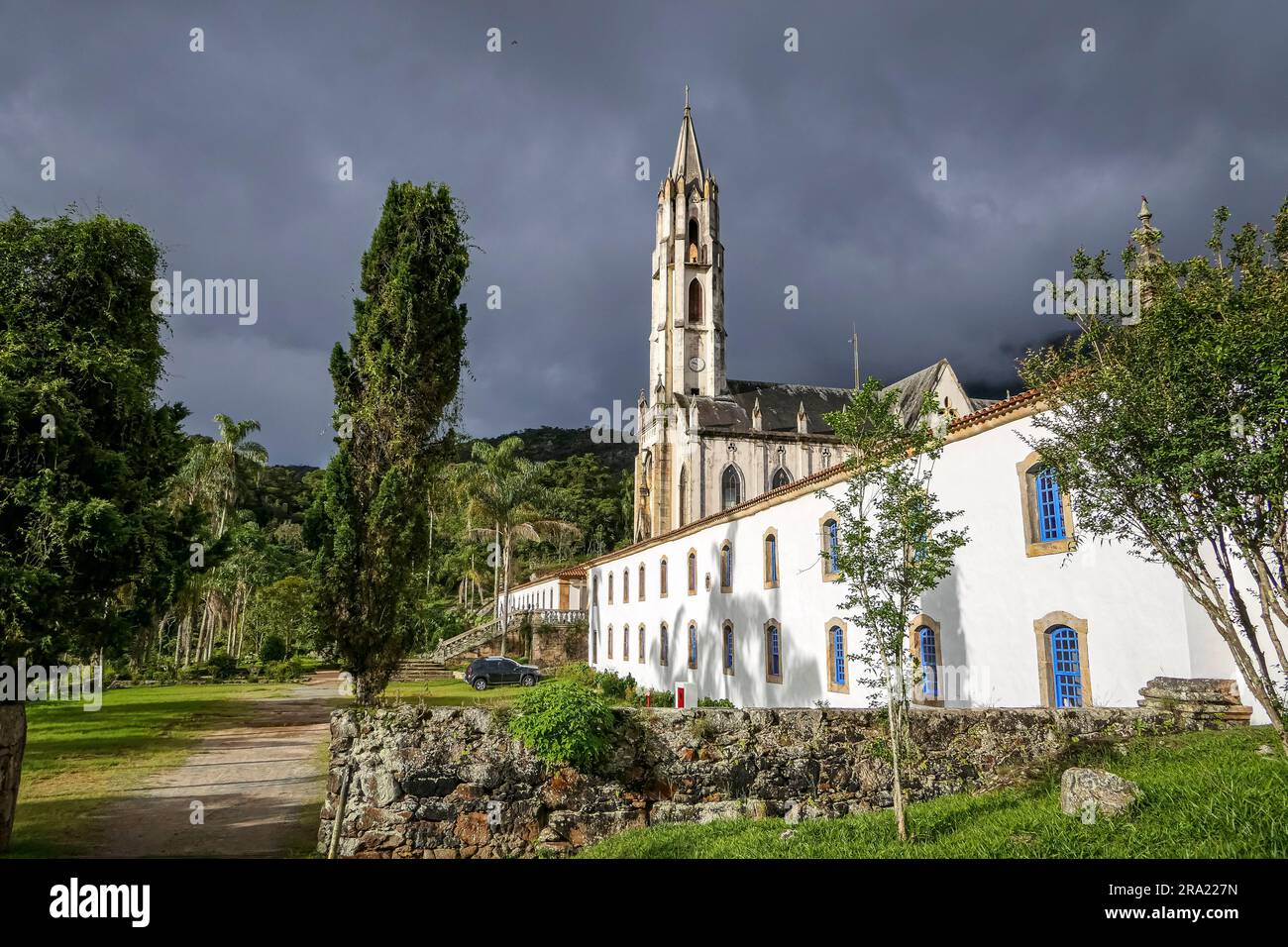 Vue sur l'église et les bâtiments en plein soleil avec des nuages gris en arrière-plan, Sanctuaire Caraça, Minas Gerais, Brésil Banque D'Images