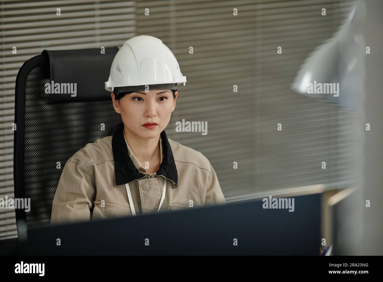 Portrait d'une femme asiatique portant un casque de sécurité sur le lieu de travail au bureau et utilisant un ordinateur, un espace de copie Banque D'Images