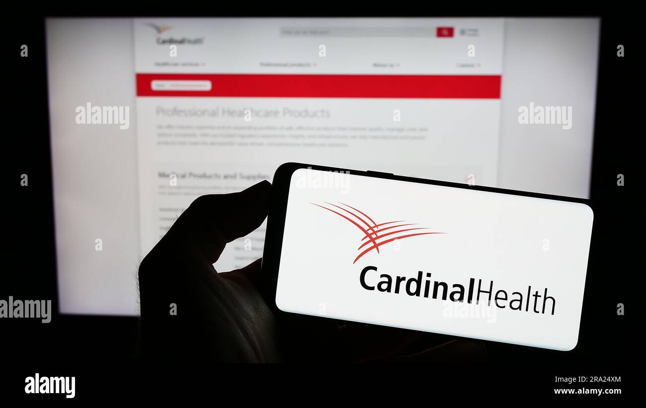 Personne tenant un téléphone portable avec le logo de la société américaine de soins de santé Cardinal Health Inc. Sur l'écran devant la page Web. Concentrez-vous sur l'affichage du téléphone. Banque D'Images