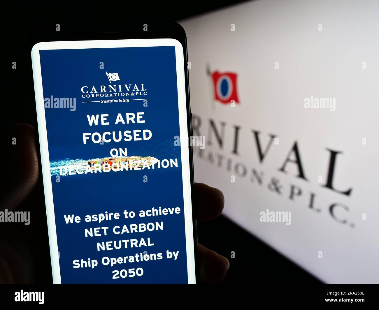 Personne tenant un téléphone portable avec la page web de la compagnie de croisière Carnival Corporation plc à l'écran devant le logo. Concentrez-vous sur le centre de l'écran du téléphone. Banque D'Images