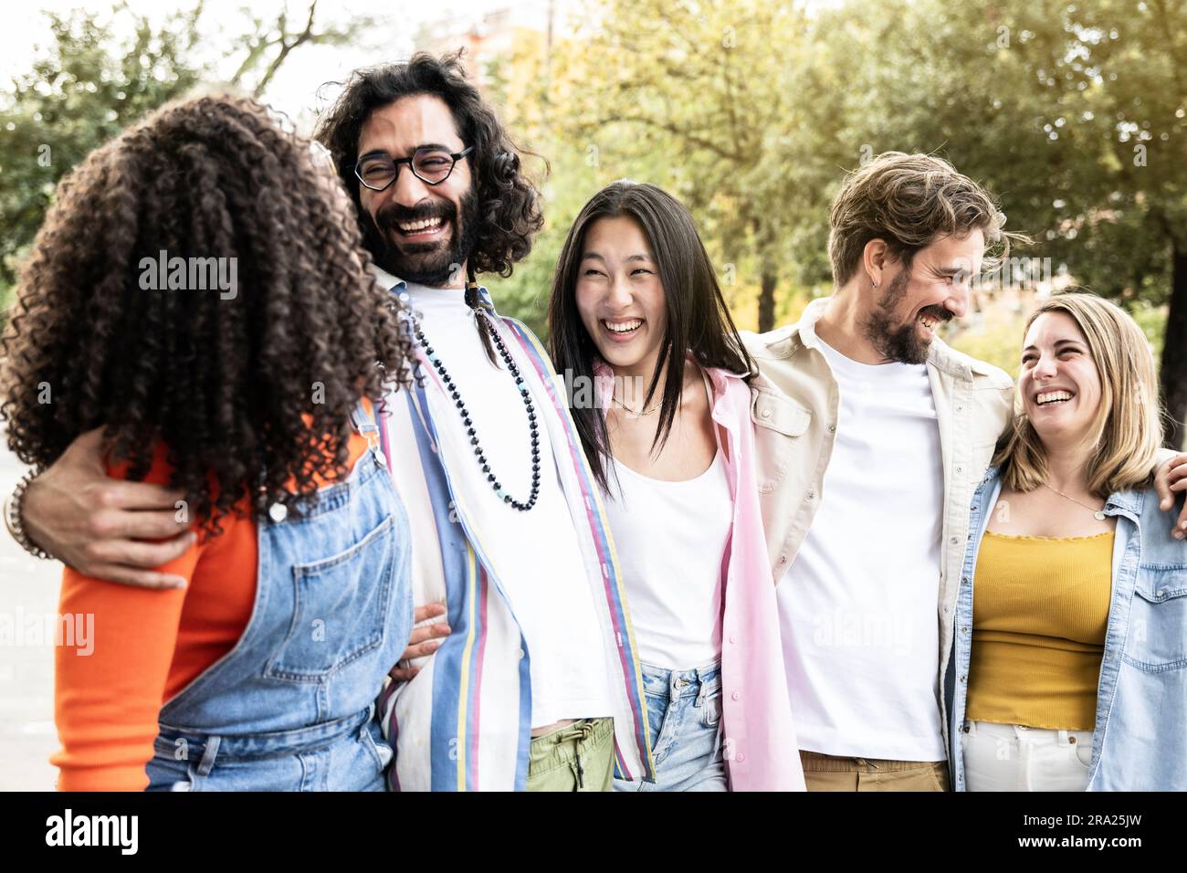 Groupe multiethnique d'amis s'amusant ensemble regardant dans la rue.divers jeunes femmes et hommes s'embrassant les uns les autres riant et insouciant Banque D'Images