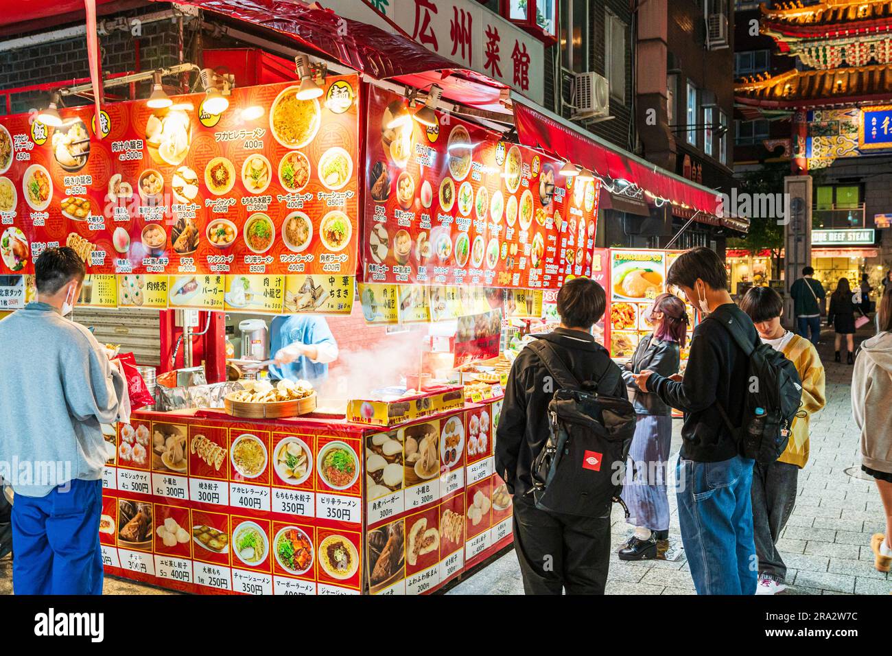 Grand coin de rue vendant des fast-foods chinois, dont des petits pains et des boulettes à la vapeur, devant un restaurant près de l'Eastern Gate, Chinatown à Kobe. Nuit. Banque D'Images