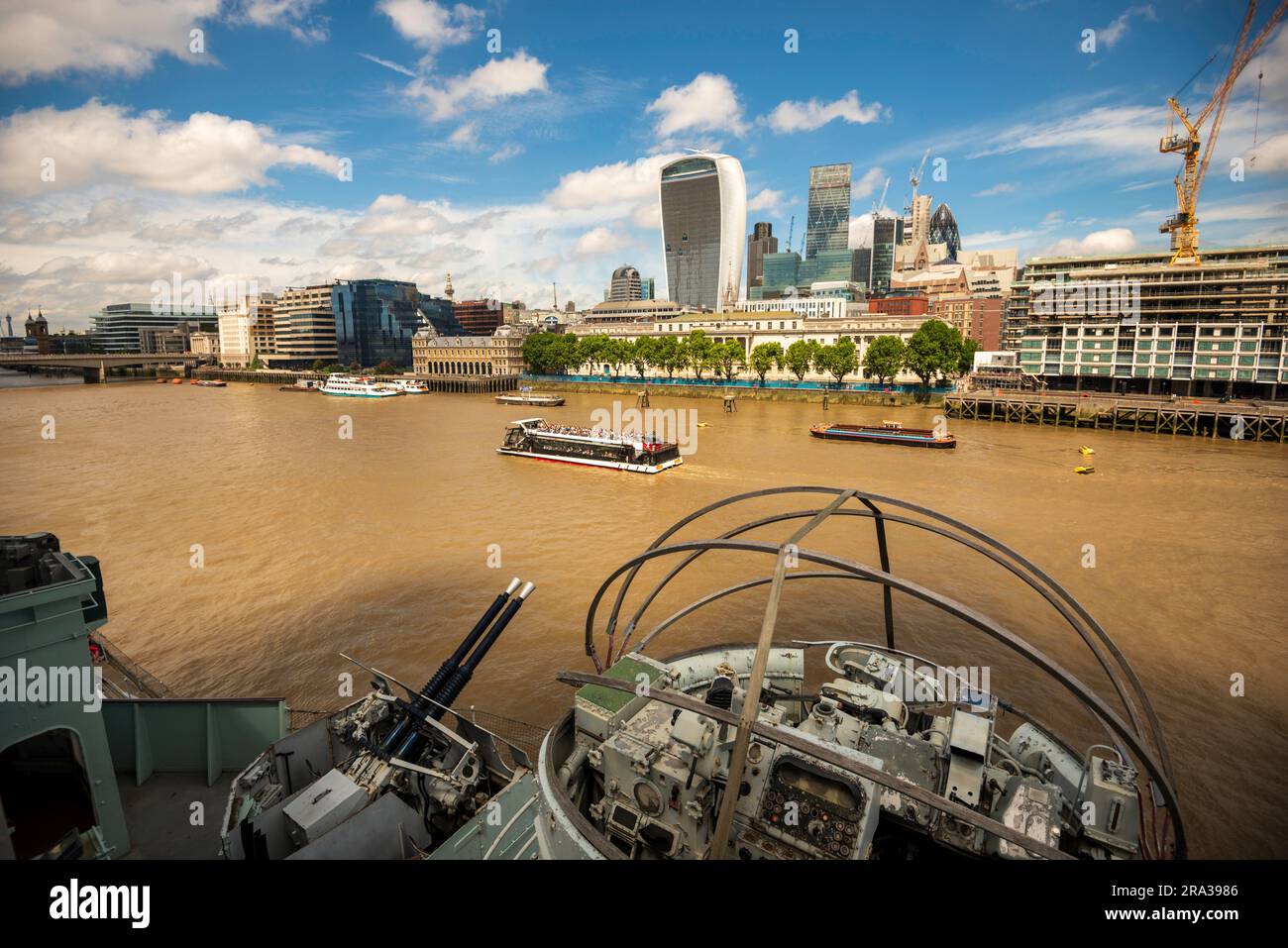 Paysage urbain londonien, vue panoramique sur le navire HMS Belfast sur la Tamise avec des bâtiments de la ville, des gratte-ciel et des bateaux d'excursion remplis de touristes. Banque D'Images