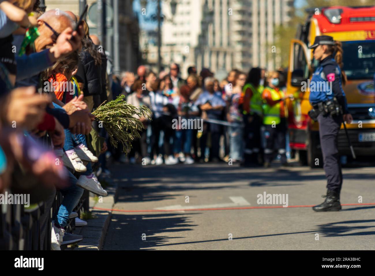 Une policière espagnole garde la foule des spectateurs du défilé lors d'une procession de la semaine Sainte à Madrid, en Espagne, le dimanche des Rameaux pendant Semana Santa. Banque D'Images