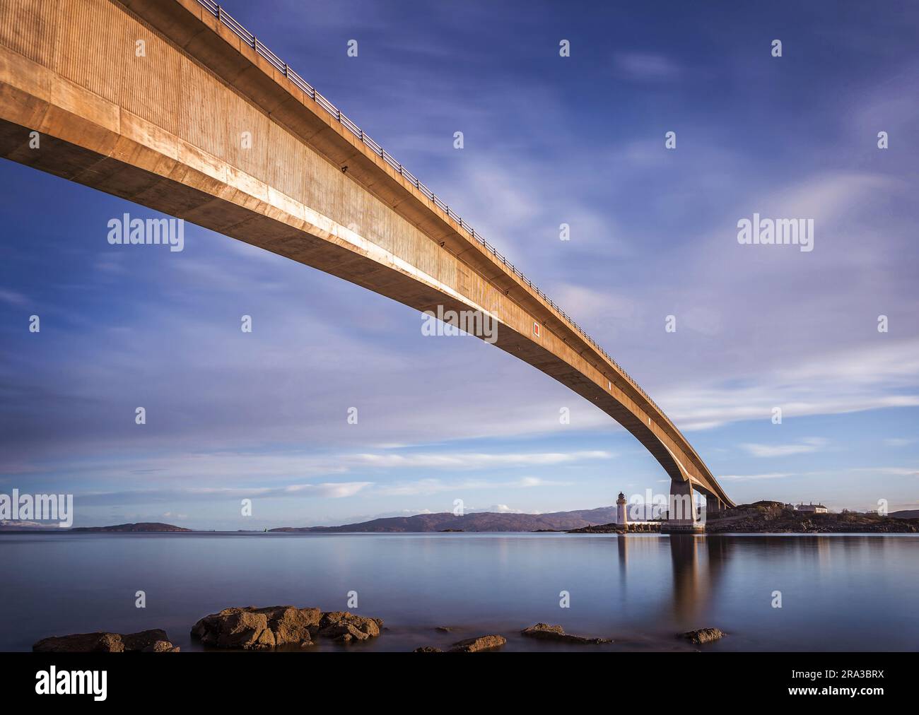 Île de Skye, Écosse - le célèbre pont de Skye brillant d'or tôt le matin avec ciel bleu et phare à l'arrière-plan Banque D'Images