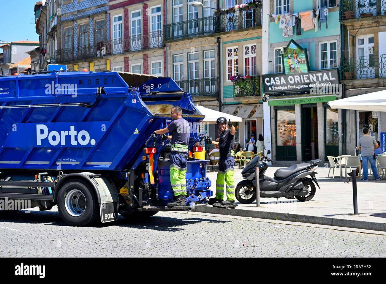 Véhicule de collecte des ordures du conseil municipal dans la rue de la ville avec des hommes à l'arrière, Porto, Portugal Banque D'Images