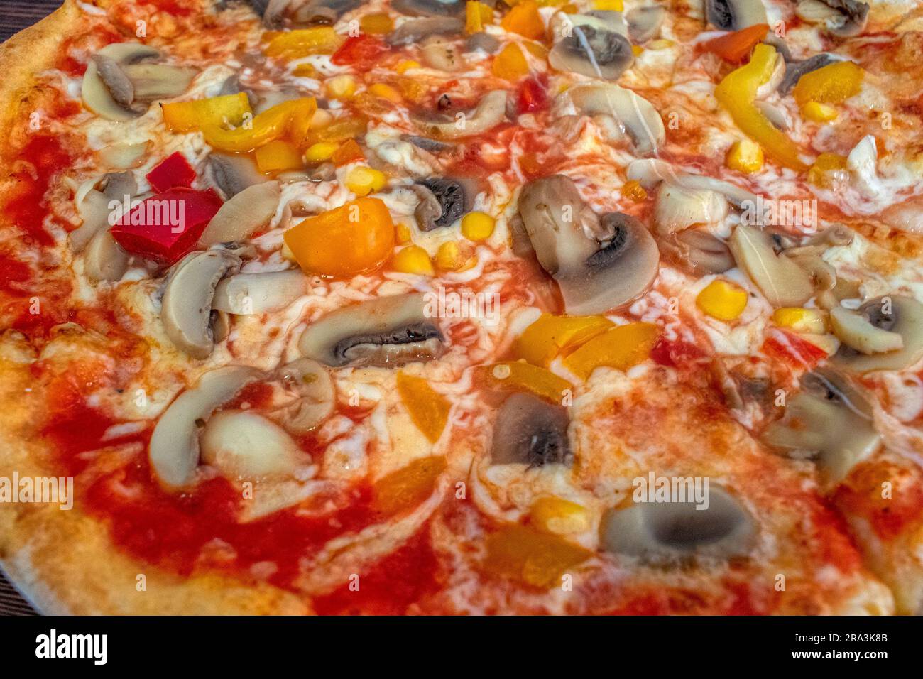 Pizza Funghi : une pizza appétissante recouverte de sauce tomate, de fromage fondu, de champignons savoureux, de poivrons vifs et de maïs doux, tous servis sur un rus Banque D'Images