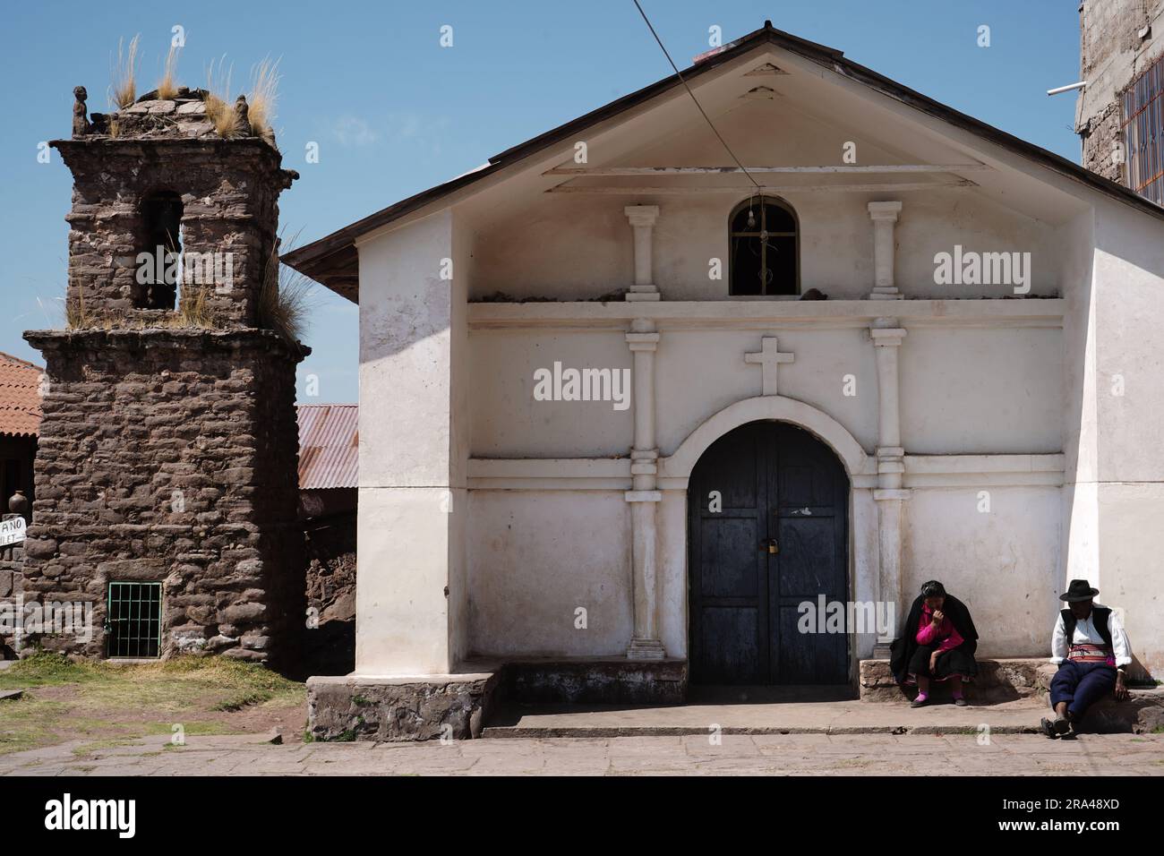 Des habitants assis devant une église sur l'île Taquile Banque D'Images