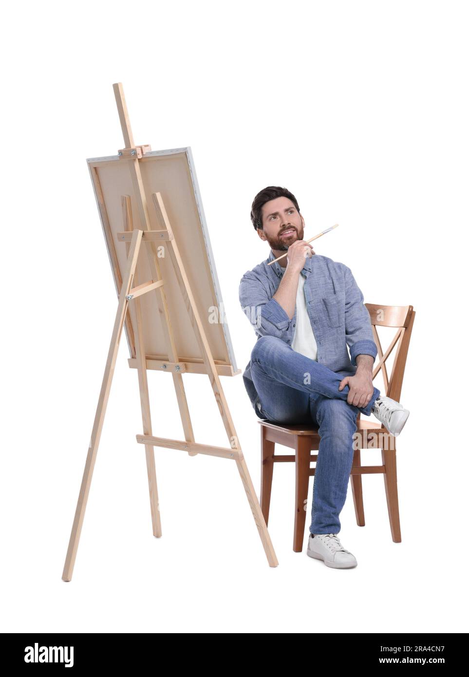 Homme avec peinture au pinceau sur fond blanc. Utilisation du chevalet pour tenir la toile Banque D'Images