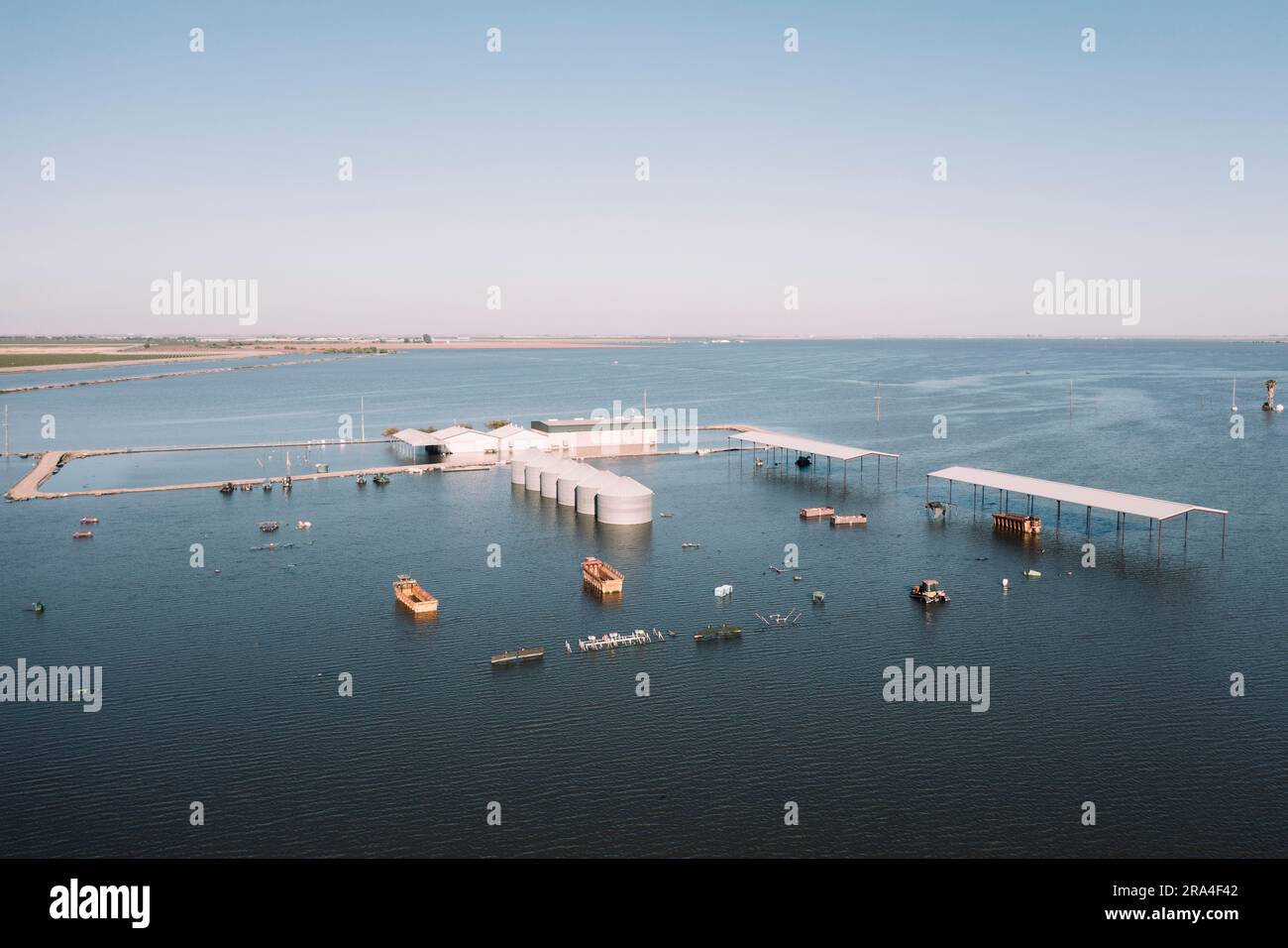 Les ranchs inondés et le matériel agricole couvrent une vaste étendue de la vallée centrale de Californie. Le lac Tulare était autrefois le plus grand plan d'eau douce de l'Ouest américain. Il s’est asséché il y a un siècle après que ses affluents aient été damés, dikés et détournés et que le lit du lac ait été converti en une des terres agricoles les plus fertiles et productives de Californie. En 2023, le lac Tulare a fait une réapparition surprise après un hiver de pluies exceptionnellement fortes, inondant quelque 180 000 kilomètres carrés de terres agricoles dans la vallée centrale. Les experts croient qu'il faudra peut-être deux ou trois ans pour que les eaux inondées se soient retirées. Banque D'Images