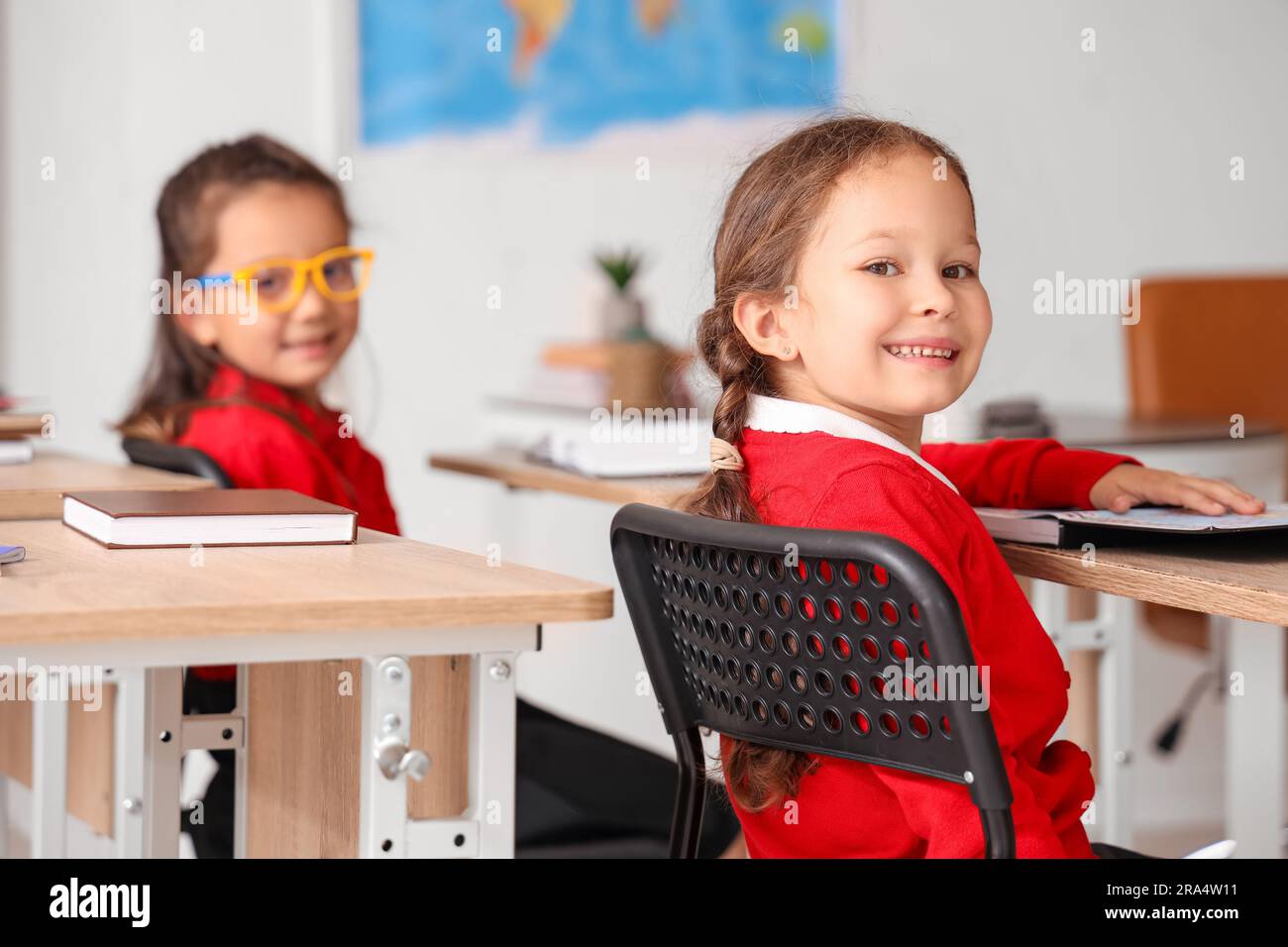 Petites écolières assises aux bureaux dans la salle de classe Banque D'Images