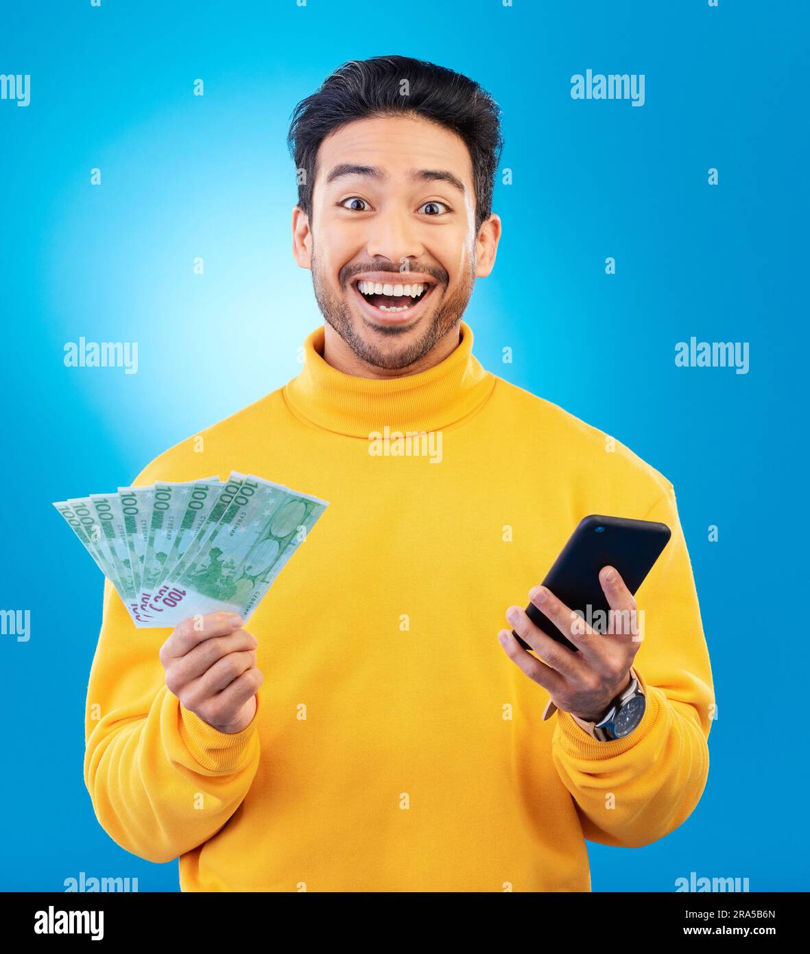 Gagnant, argent et portrait de l'homme asiatique avec téléphone en studio pour le bonus en ligne, la compétition et la loterie. Succès, finance et homme personne sur bleu Banque D'Images