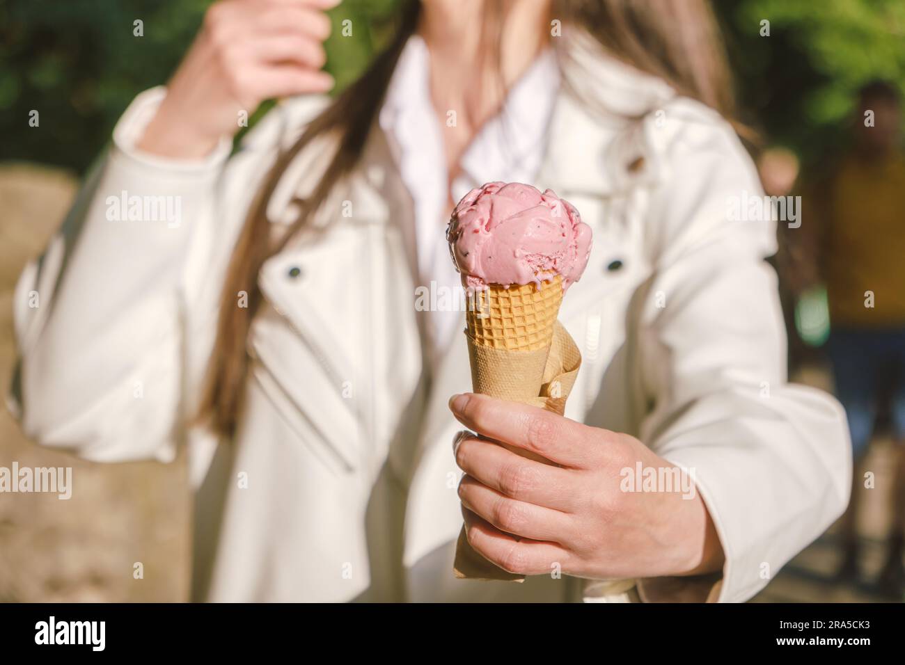 Une femme offre de la glace à gaufres à un ami le jour de l'été. Banque D'Images