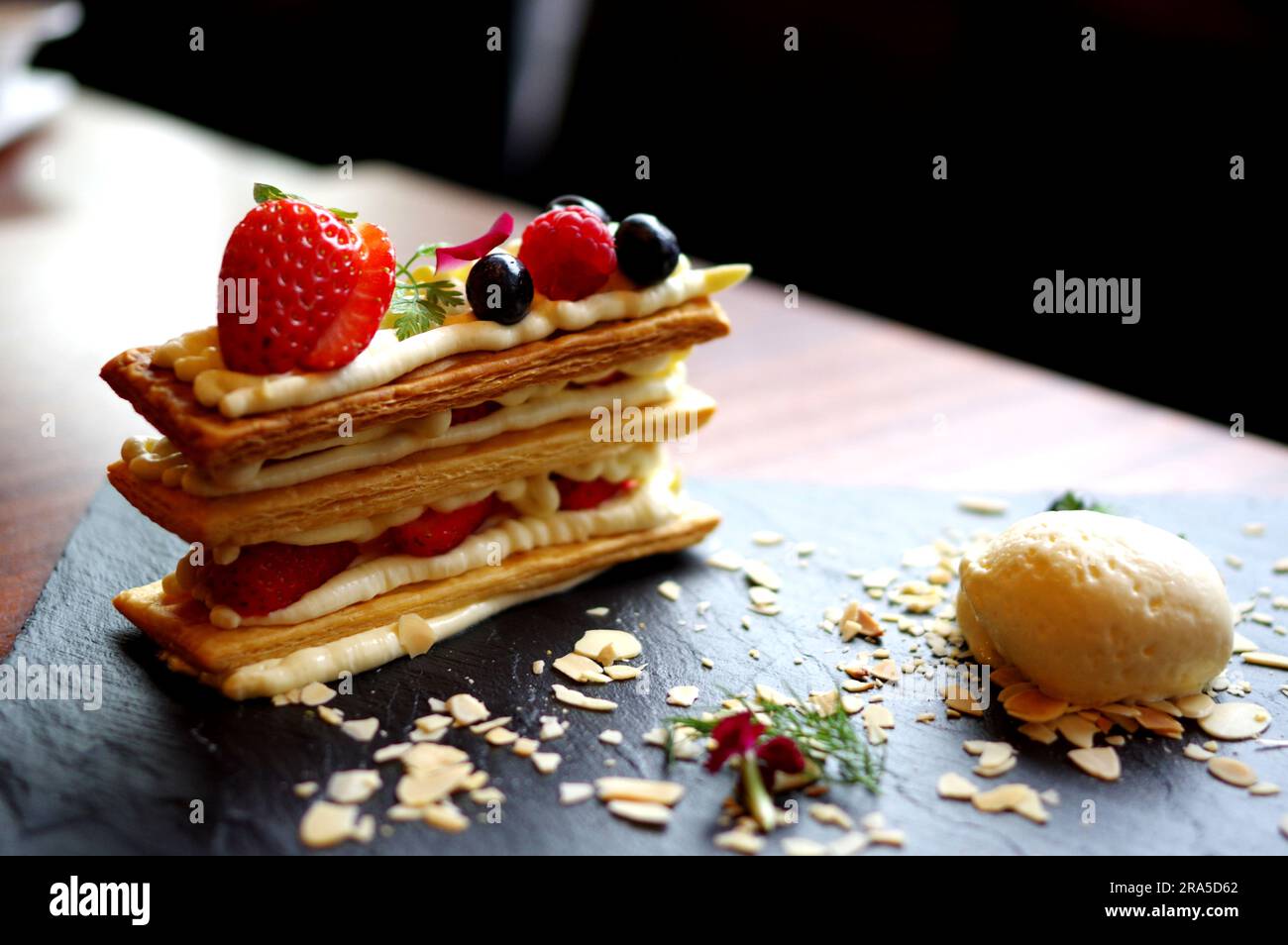 Fraise myrtille framboise jaune feuille de crème glacée sur plaque d'ardoise noire dessert délicat du café Banque D'Images