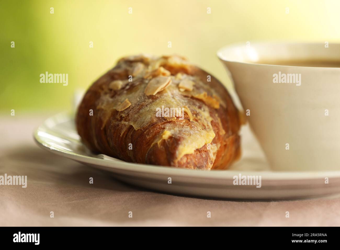 Un croissant aux amandes et une tasse de café Banque D'Images