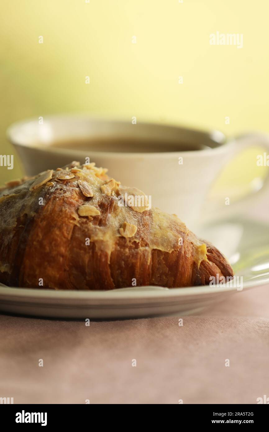 Un croissant aux amandes et une tasse de café Banque D'Images