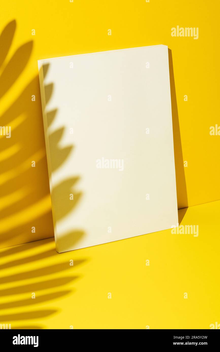 Maquette de magazine blanche vierge, modèle sur fond jaune avec ombre tropicale de feuilles de palmier. Banque D'Images
