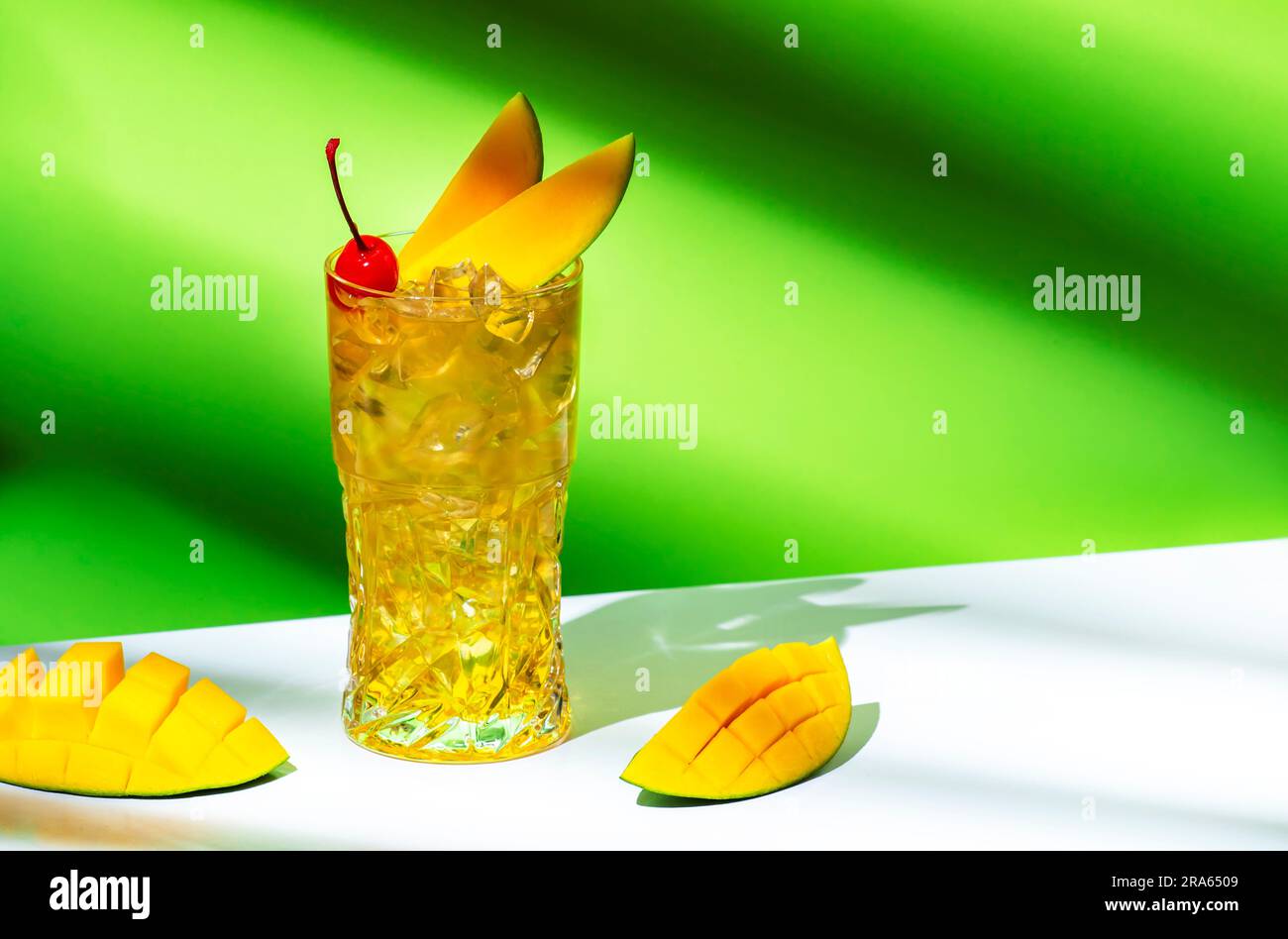 Mango Rum collins cocktail alcoolique au rhum, au sirop, à la bière au  gingembre, au jus de citron, à la glace et à la mangue fraîche.  Arrière-plan vert, espace de copie Photo
