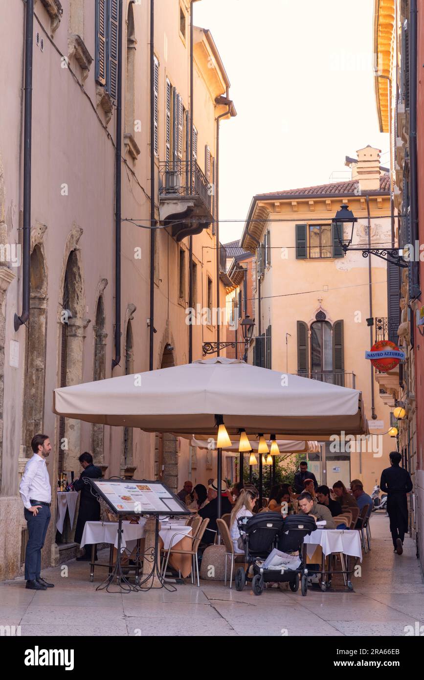 Restaurant Vérone ; les gens assis à manger à des tables à l'extérieur le soir dans un restaurant de rue, vieille ville de Vérone, Vérone Italie Europe. Italie voyage Banque D'Images