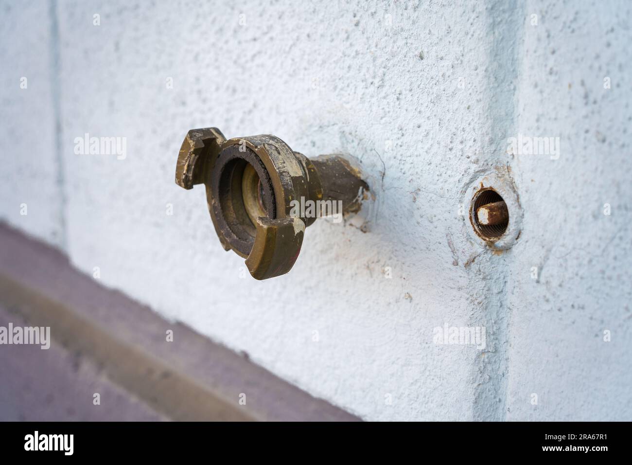 Raccord de tuyau d'eau extérieur sur un mur en béton blanc. Banque D'Images