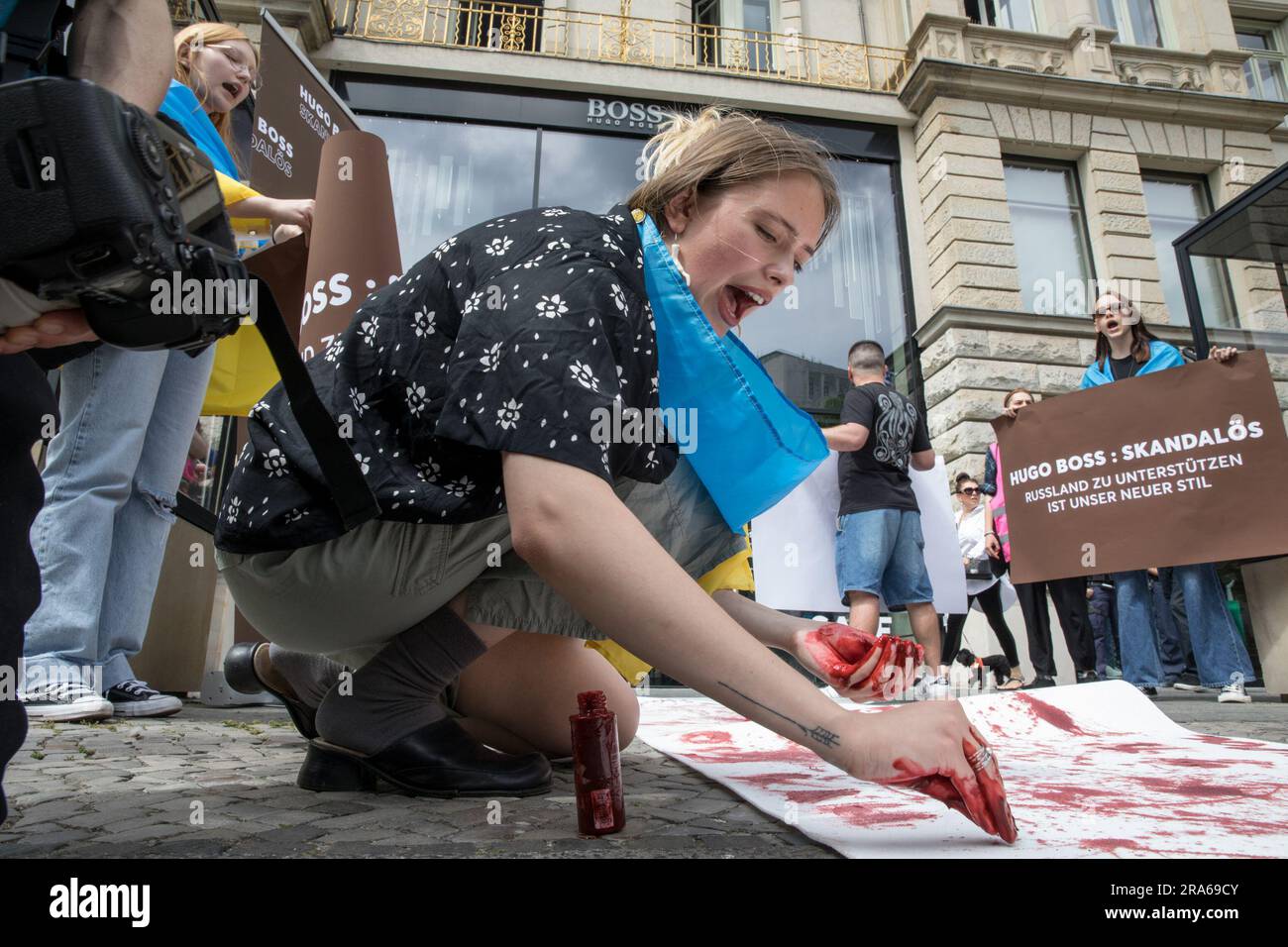 Berlin, Allemagne. 01st juillet 2023. 1 juillet 2023, Berlin, Allemagne: À Berlin, le magasin Hugo Boss, un phare de la mode de luxe allemande, est devenu le théâtre d'une manifestation sur 1 juillet 2023. Drapés de drapeaux ukrainiens, les manifestants se sont rassemblés devant le magasin, transformant le centre de la mode haut de gamme en un lieu d'expression politique et de résistance. Le message des manifestants était clair et précis : « Hugo Boss, scandaleux ! » C'était leur cri de ralliement, une réprimande directe de la poursuite des opérations commerciales de l'entreprise en Russie malgré le conflit en cours avec l'Ukraine. ''pas d'affaires avec la Russie, '' ils ont chanté, Th Banque D'Images