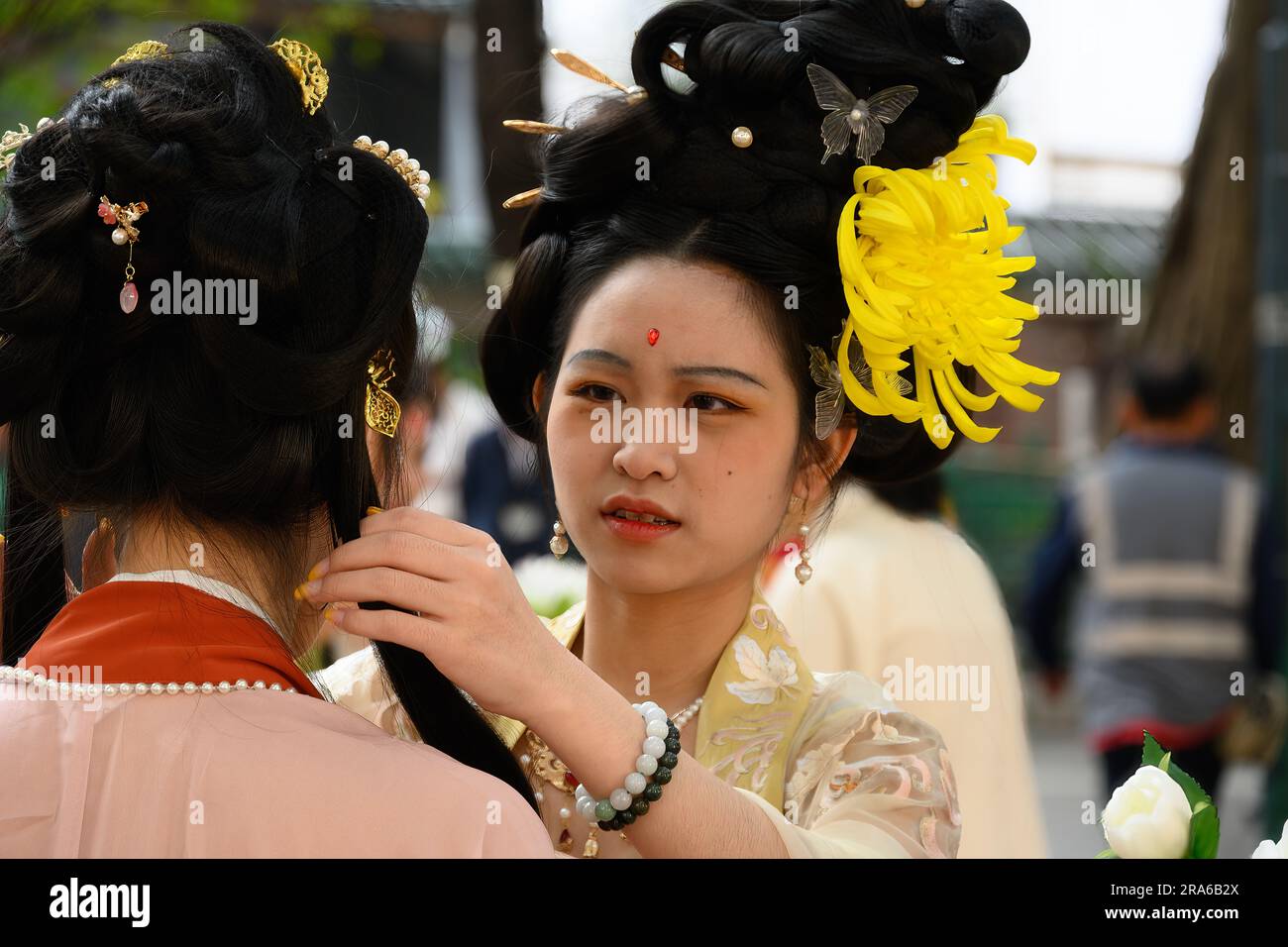 Hong Kong, Chine -- 11 mars 2023. Une femme chinoise vêtue d'une tenue de mariage jaune aide une amie avec ses cheveux. Banque D'Images